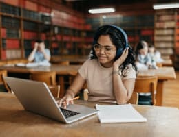 a woman using a laptop and wearing headphones
