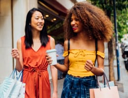 two women walking outside and holding shopping bags