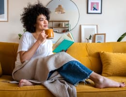 a woman sitting on a couch and holding a coffee mug